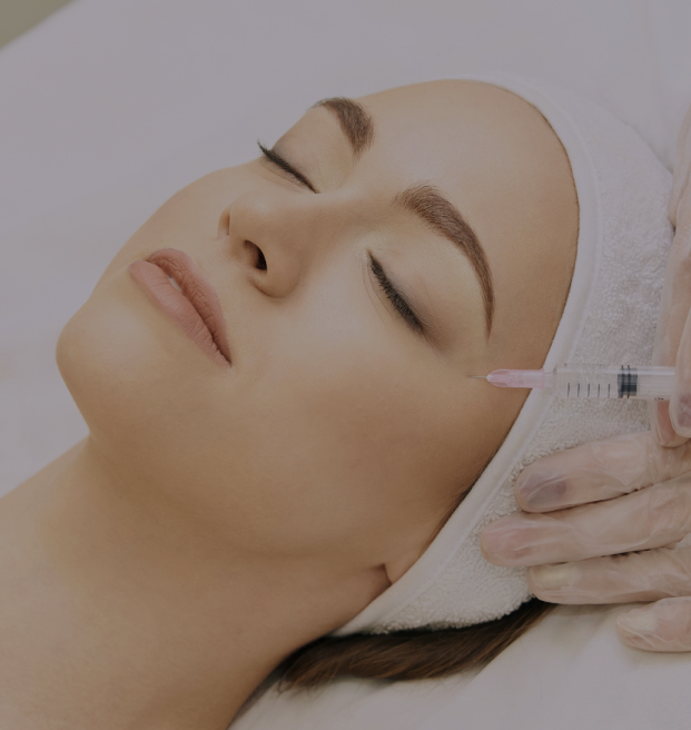 Woman lying down with eyes closed getting cosmetic injections in her cheeks